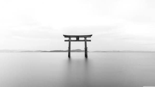 A torii gate standing alone in still water